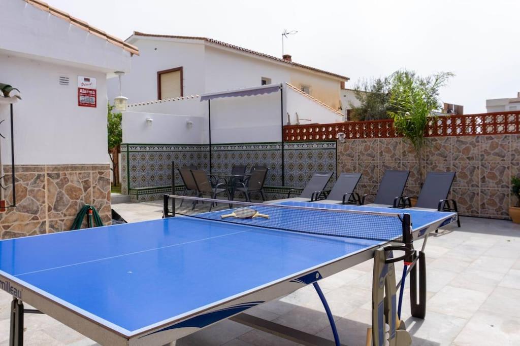 2 tafeltennistafels op een patio met stoelen bij Chalet Campomar Beach Málaga in Torre de Benagalbón