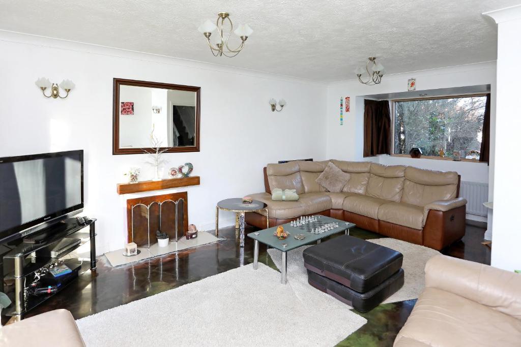uma sala de estar com um sofá e uma televisão em Picturesque Family Hideaway Chipping Ongar Essex em Fyfield