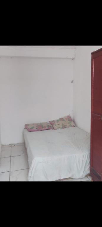 a bed in a room with a white wall at Casa de praia Jacumã in Conde