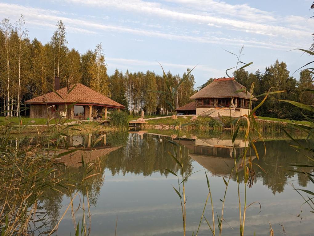 een reflectie van twee gebouwen in een waterlichaam bij Brīvdienu māja "Saules Avoti" in Talsi