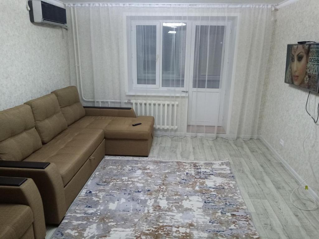 sala de estar con sofá y ventana en 3 комнатная квартира, en Uralsk