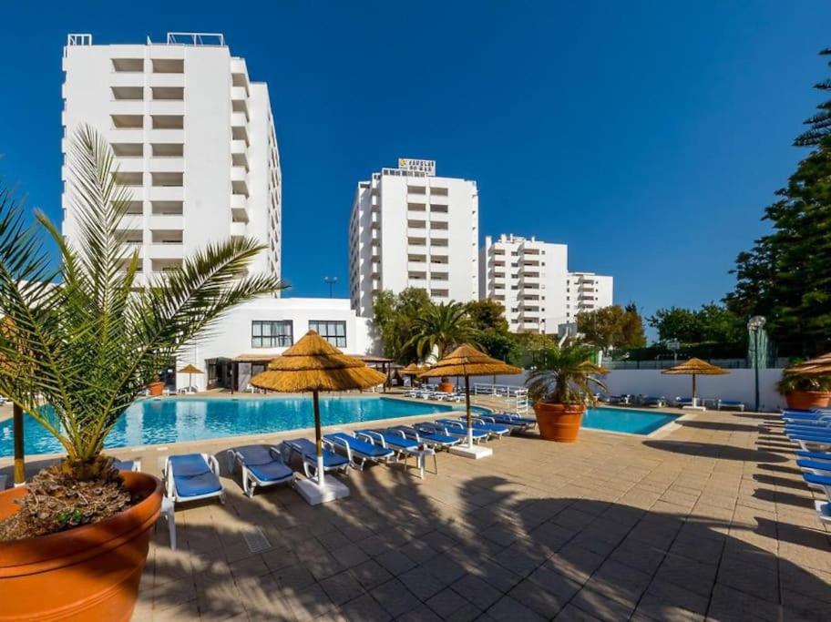 a swimming pool with chairs and umbrellas and buildings at AL Sunset in Albufeira