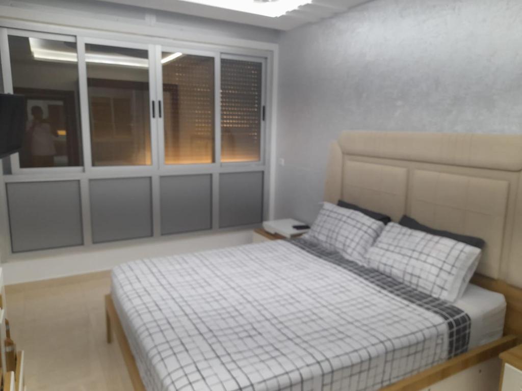 een slaapkamer met een bed in een kamer met ramen bij appartement mdiq tetouan, 2 chambres 1 double salon in M'diq