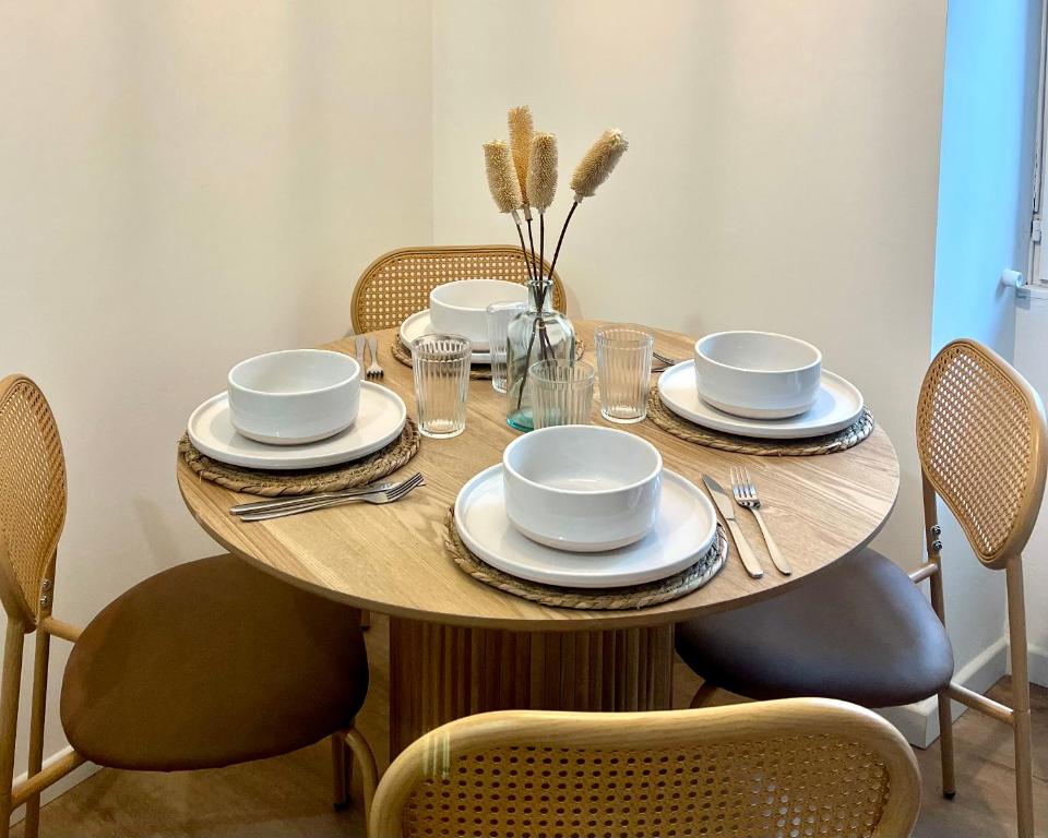einem Holztisch mit Tellern und Geschirr darauf in der Unterkunft Cocon de mimi in Aix-les-Bains