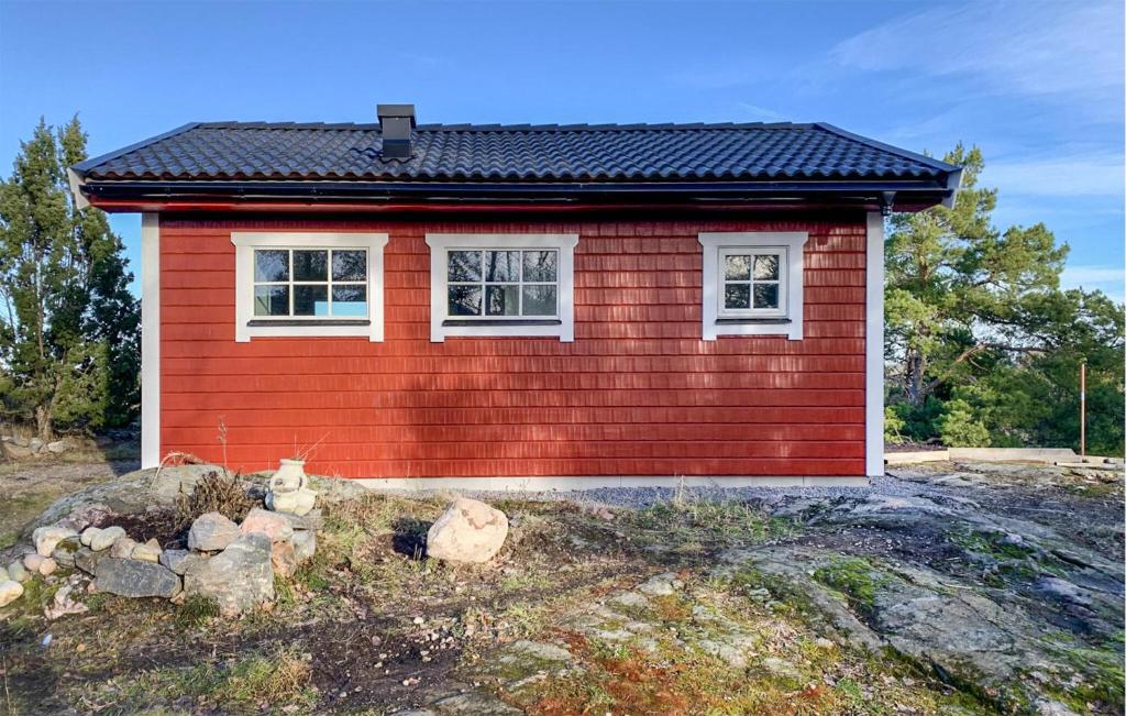 ein kleines rotes Haus mit zwei Fenstern auf einem Feld in der Unterkunft Amazing Home In Mariefred With Kitchen in Mariefred