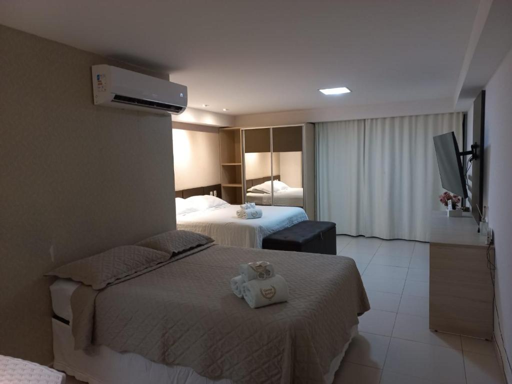 a hotel room with two beds and a television at Tabatinga Residence Service - Flat 02 in Conde