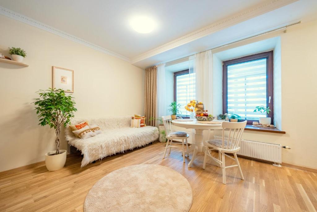 Cozy Suite Roomita في فيلنيوس: غرفة معيشة مع أريكة وطاولة