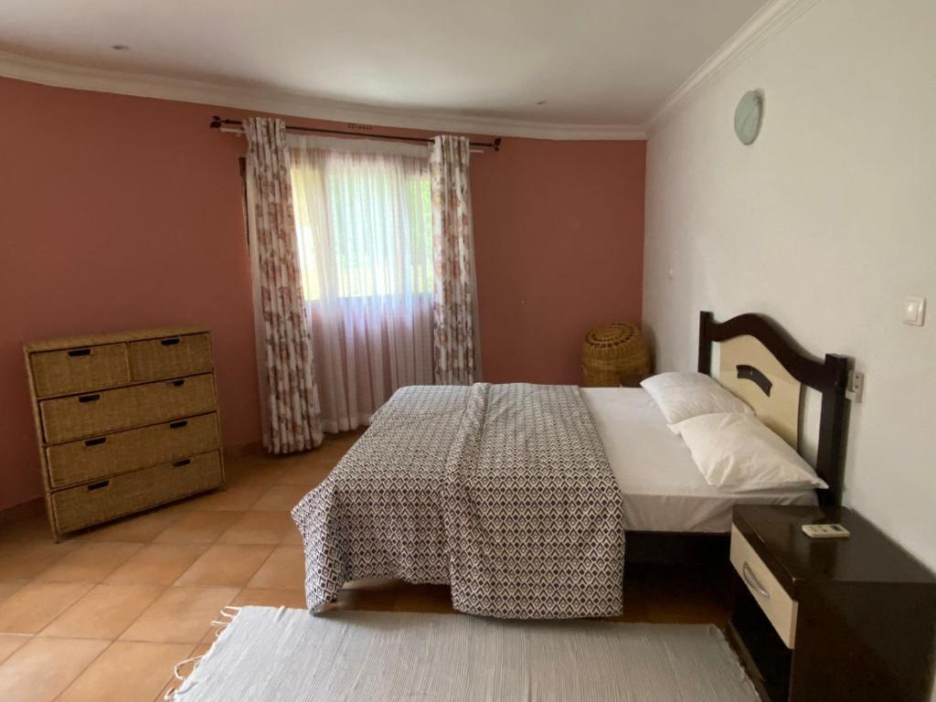 a bedroom with a bed and a dresser and a window at Vacation Home close to the beach in Bilene in Vila Praia Do Bilene