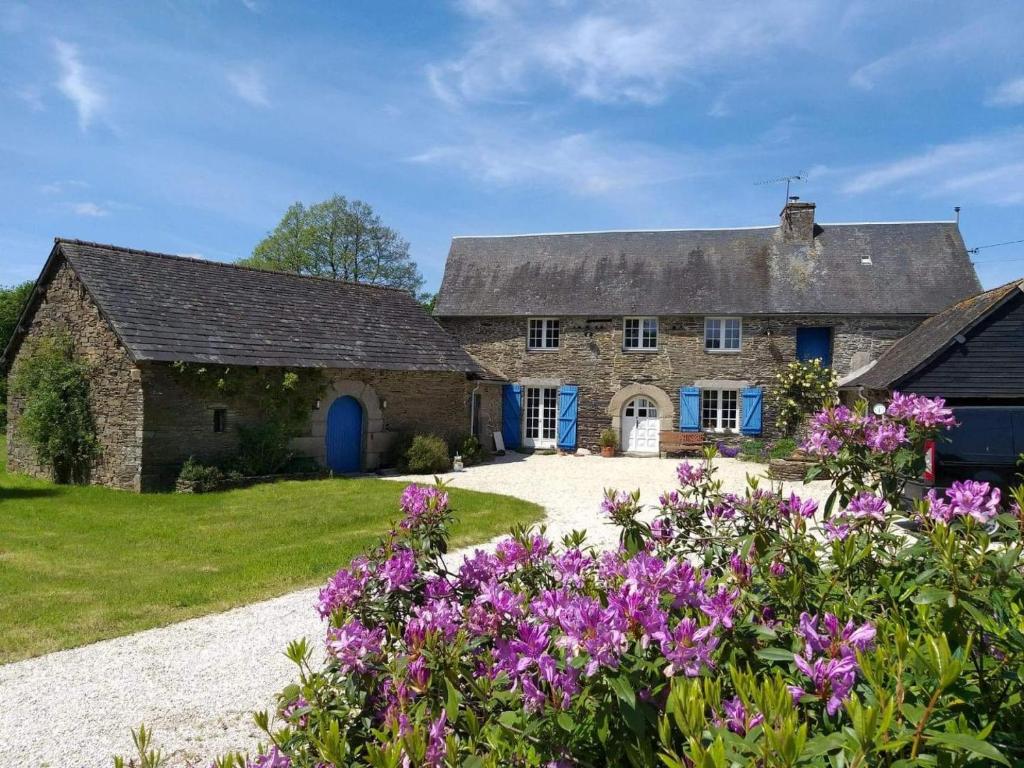 una vecchia casa in pietra con fiori viola in primo piano di Le parfum des fleurs a Plussulien