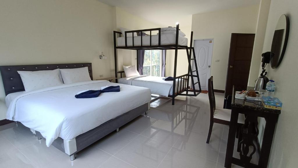 a bedroom with a large bed and a desk and a chair at Khao Sok Family Room House in Khao Sok