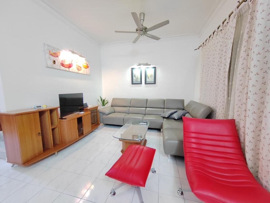 een woonkamer met een bank en rode stoelen bij Ipoh Station 18 Homestay in Ipoh