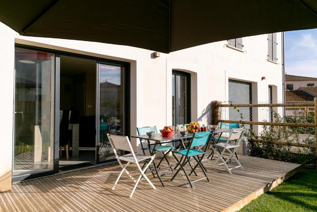 uma mesa e cadeiras num deque com um guarda-sol em Villa Paulina, cœur village, à 5 min de la plage em Portiragnes