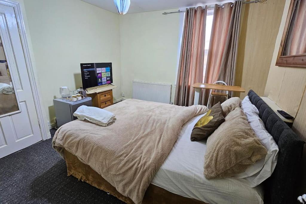 a bedroom with a large bed and a television at Affordable Private Space in Leeds