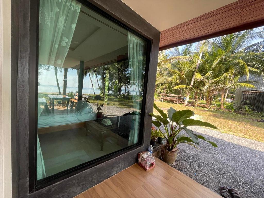 uma janela de vidro de uma casa com vista para o oceano em บ้านระเบียงเลหลังสวน 1 ห้อง em Ban Hin Sam Kon