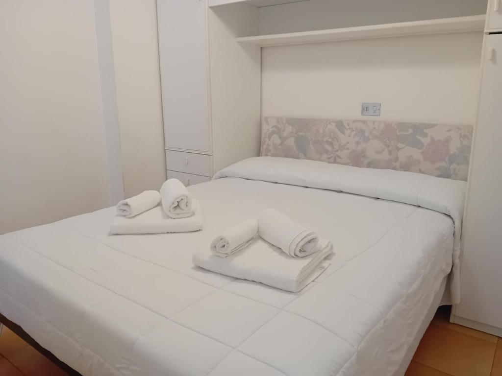 a white bedroom with two beds with towels on them at Residence Giardino in Montecreto