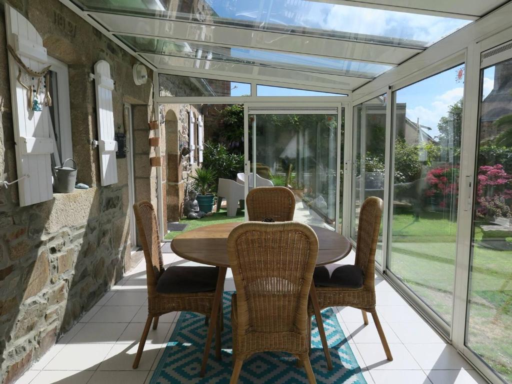 a conservatory with a table and chairs on a patio at Maison de charme 3* avec WIFI, jardin clos, véranda, à 350m du port à Perros-Guirec - FR-1-368-254 in Perros-Guirec