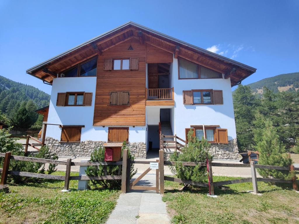 una casa en las montañas con una valla en Hostdomus - Chalet Sciatori Loft, en Pragelato