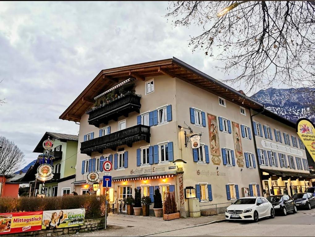 duży budynek z niebieskimi oknami i samochodami zaparkowanymi na zewnątrz w obiekcie Golden GaPa "Gasthof zum Lamm" w Garmisch Partenkirchen