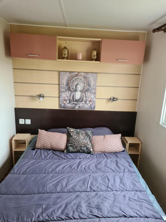 Schlafzimmer mit einem Bett mit lila Bettwäsche und Kissen in der Unterkunft Mobil-home 5 places in La Boissière-de-Montaigu
