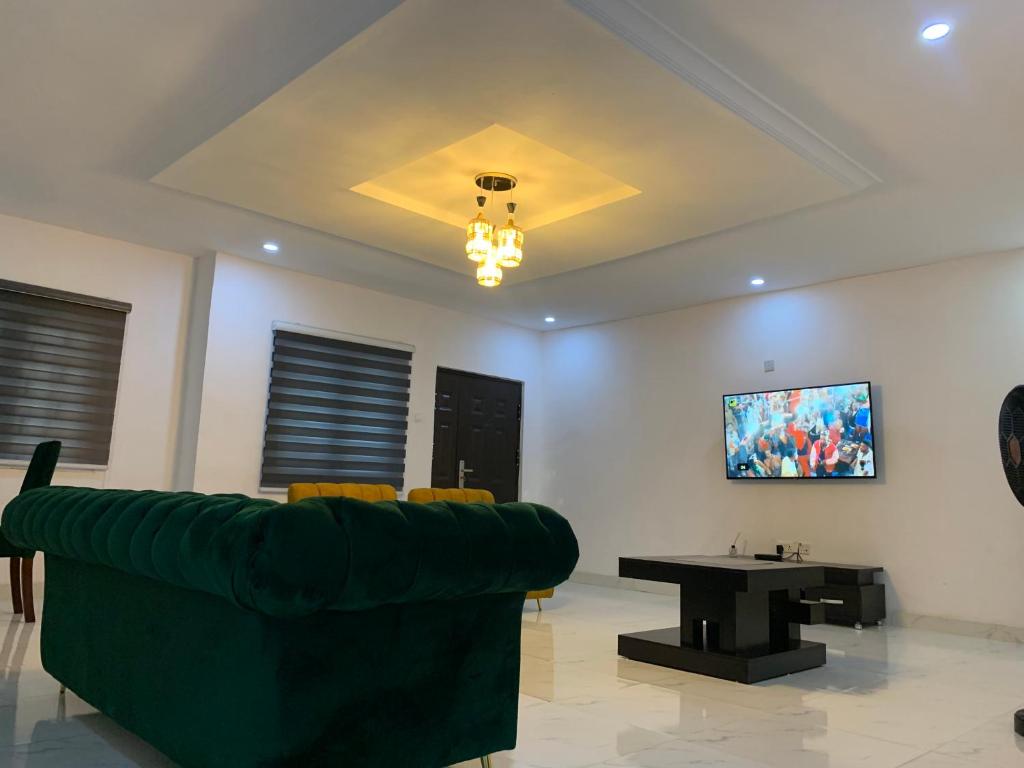 sala de estar con sofá verde y mesa en Charming & Cozy 1-BDR Apt - Mini Flat - 247 Power, Kitchen, Wi-Fi, DSTV, Netflix, 5 mins from the Airports en Ikeja