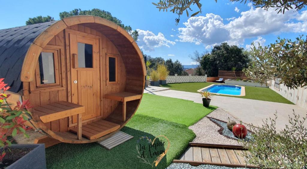 ein Holzhobbit-Haus in einem Garten mit Pool in der Unterkunft La pépite d'amour in Sainte-Anastasie-sur-Issole
