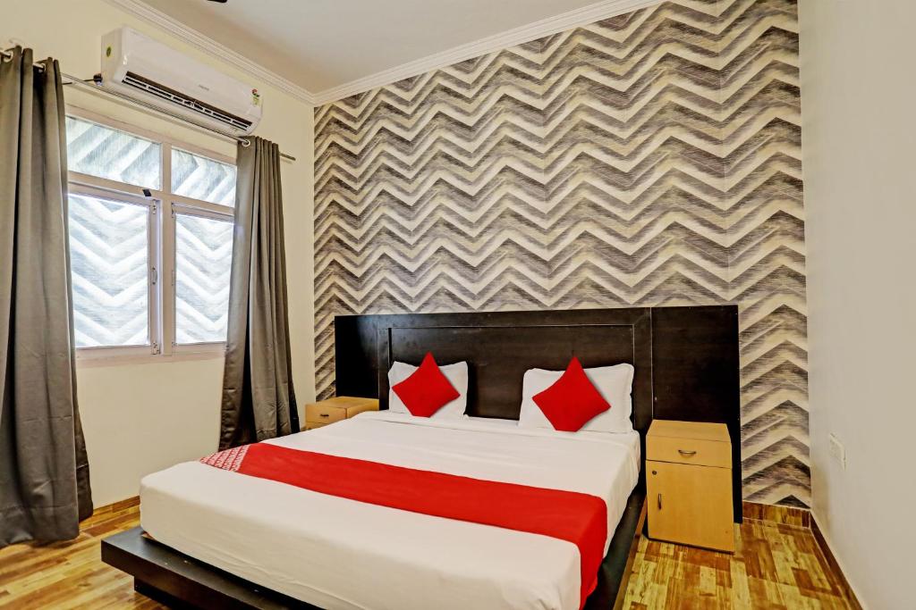 a bedroom with a large bed with red pillows at OYO Flagship Hotel Jagdambey Residency in Noida