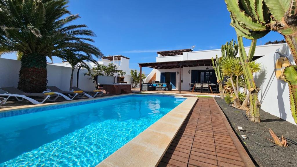 een zwembad met palmbomen en een huis bij Villa Angelita in Playa Blanca