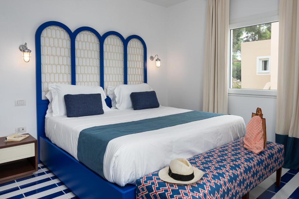a bedroom with a blue and white bed and a window at Villa Lia Hotel Capri in Capri