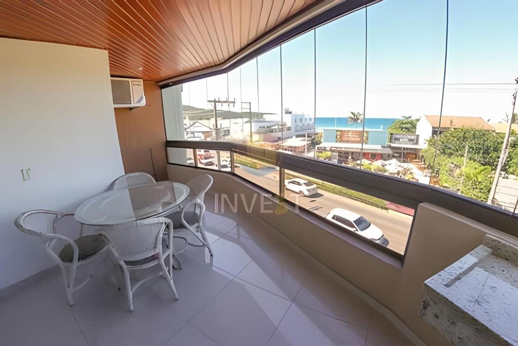 a dining room with a table and chairs and a large window at Apartamento com vista mar e excelente localização in Bombinhas
