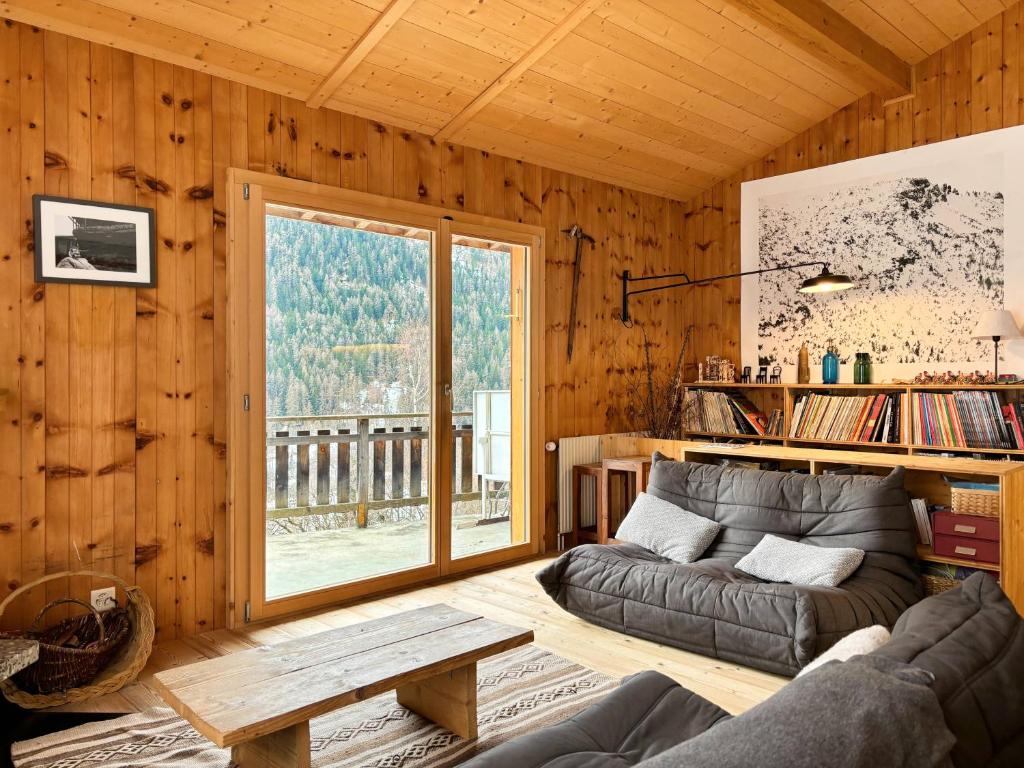 a living room with a couch and a large window at Chalet Marolly - Evolène in Evolène