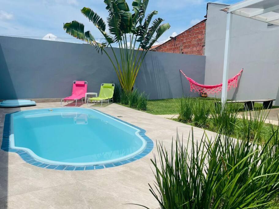 a swimming pool in a yard with two chairs and a fence at Casa com Piscina e ótimo custo benefício!! in Brotas