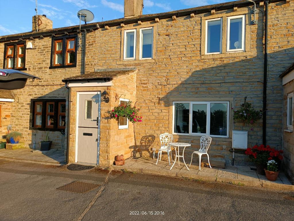 a brick house with a table and chairs outside at Hop Cottage in Mirfield