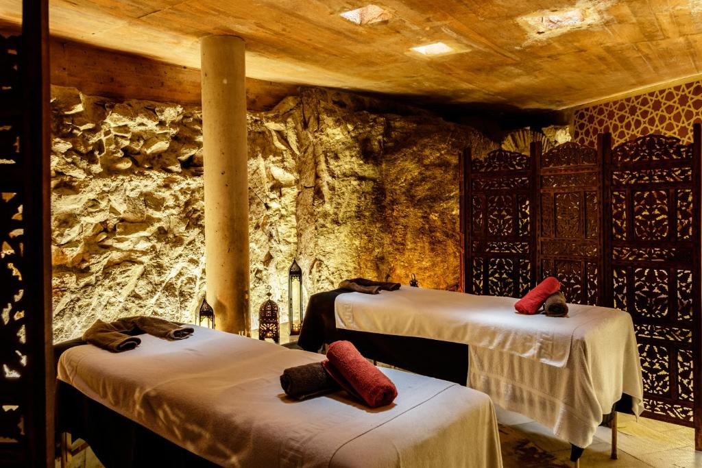Cette chambre comprend 2 lits et un mur en pierre. dans l'établissement Entre Dos Aguas Hotel Boutique, à Tolède