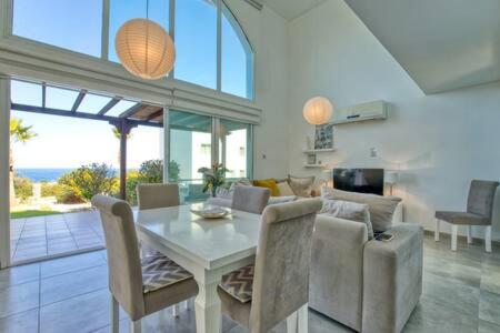 sala de estar con mesa blanca y sillas en Joya Cyprus Sugarberry Garden Apartment, en Saint Amvrosios