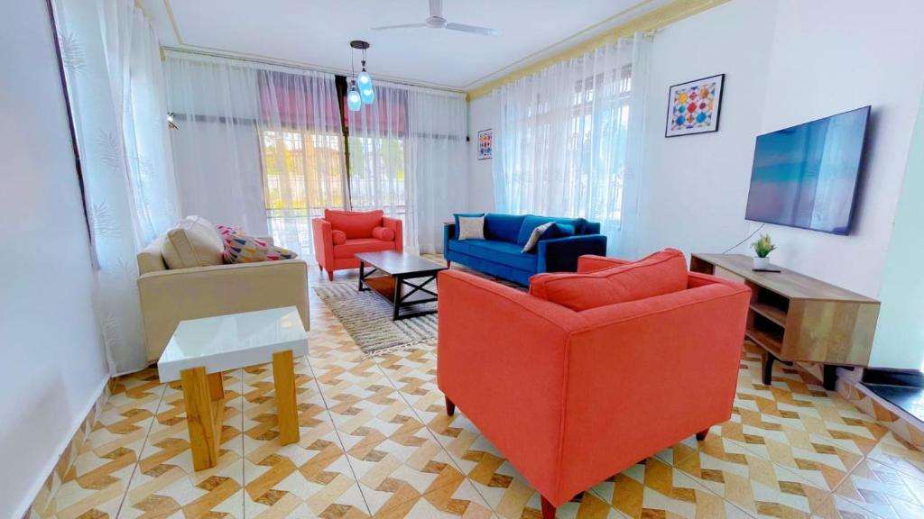 un soggiorno con sedie rosse e blu e un pianoforte di Villa Ella a Mombasa