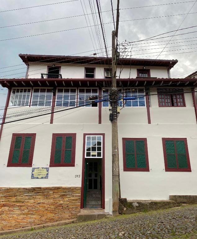 a white house with red windows and a door at Casa do Alferes in Ouro Preto