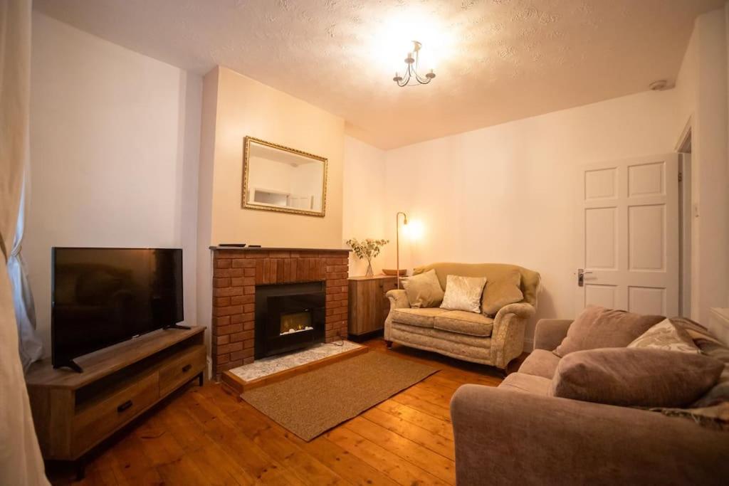 a living room with a couch and a tv and a fireplace at Birchmore House, by RentMyHouse 