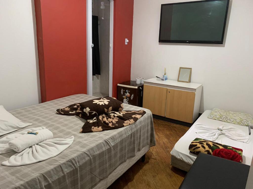 a bedroom with two beds and a flat screen tv at casa de praia in Santos