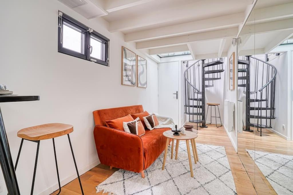 ein Wohnzimmer mit einem orangenen Sofa und einem Tisch in der Unterkunft Loft proche Montparnasse in Paris