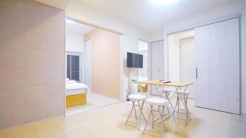 Habitación blanca con mesa y taburetes. en TOKYO SHINJUKU MIO HOTEL, en Tokio