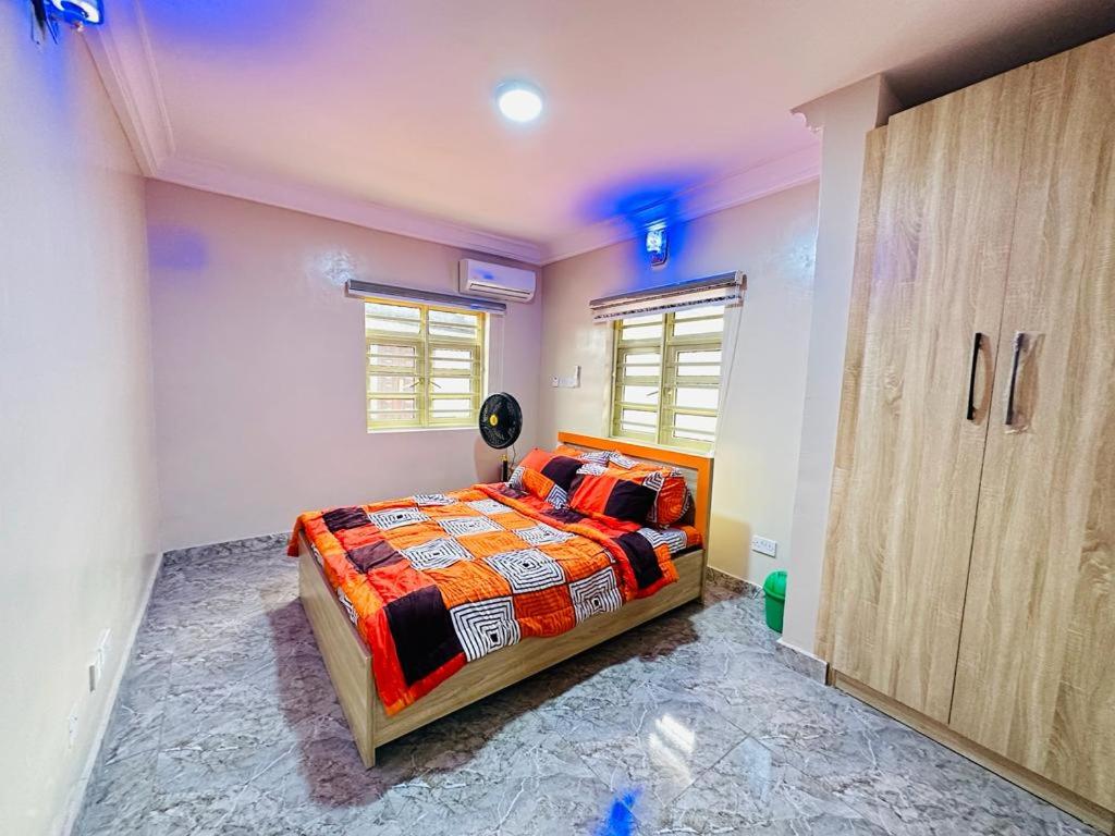 Mofide Queens Apartments (MQA) في Onigbongbo: غرفة نوم بسرير وخزانة خشبية