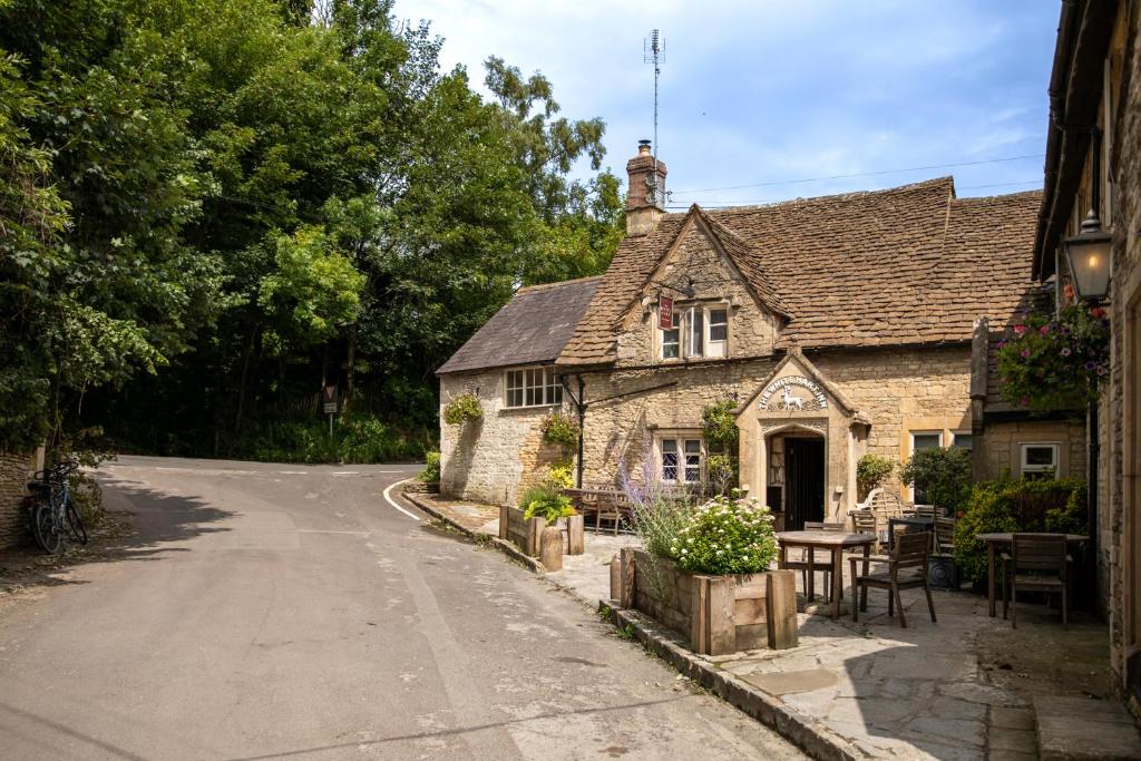 an old stone house with a table and a street at The White Hart Ford in Castle Combe