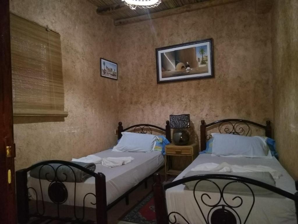 a bedroom with two beds and a mirror on the wall at Riad assriir in Tiznit