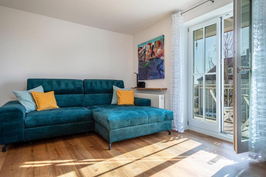 sala de estar con sofá azul y ventana en Windhager Seeblick, en Friedrichshafen