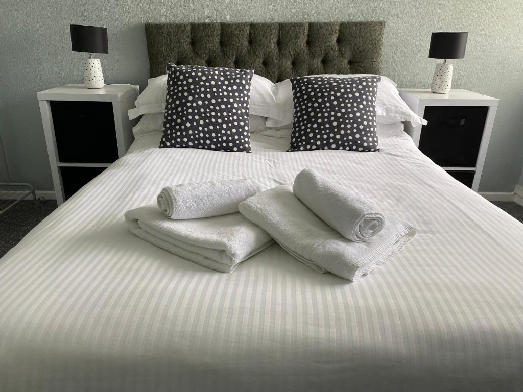 a white bed with towels and pillows on it at Quiet Ground Floor apartment with parking in Morecambe