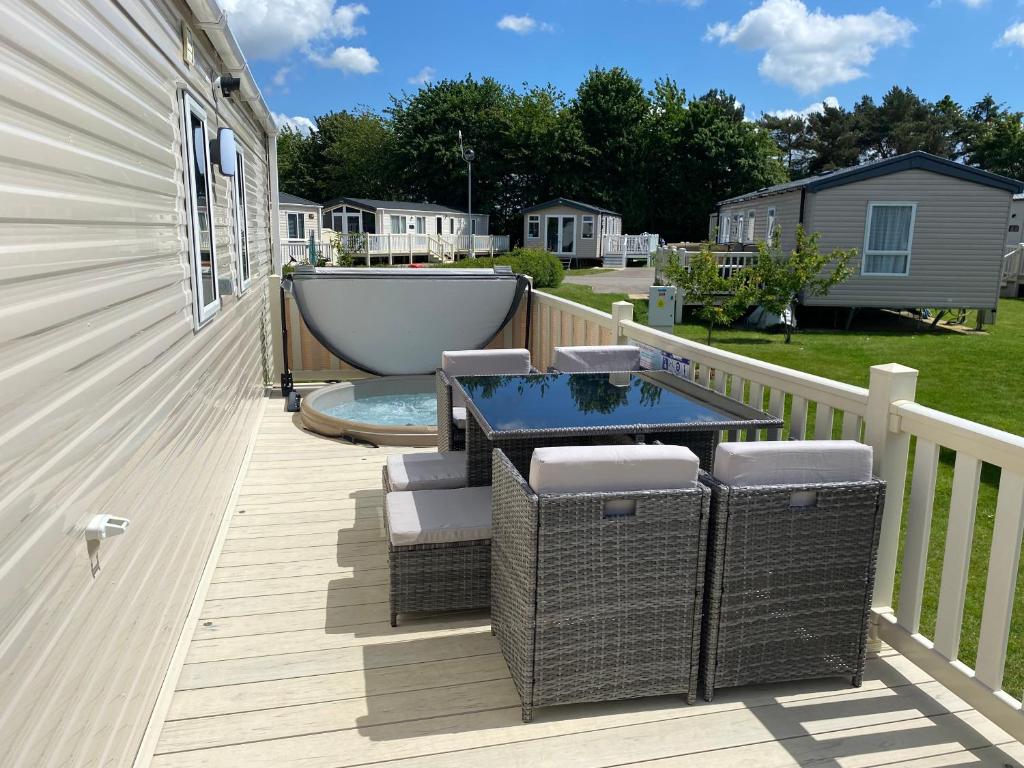 a deck with a bathtub and a table and chairs at Tattershall Lakes Kingfisher Caravan 8 berth with Hot tub & WiFi in Tattershall