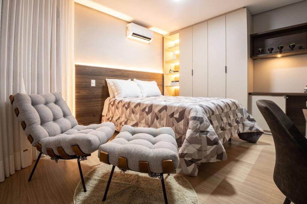 a bedroom with a bed and two chairs at Loft 804 com vista Parque Una in Pelotas