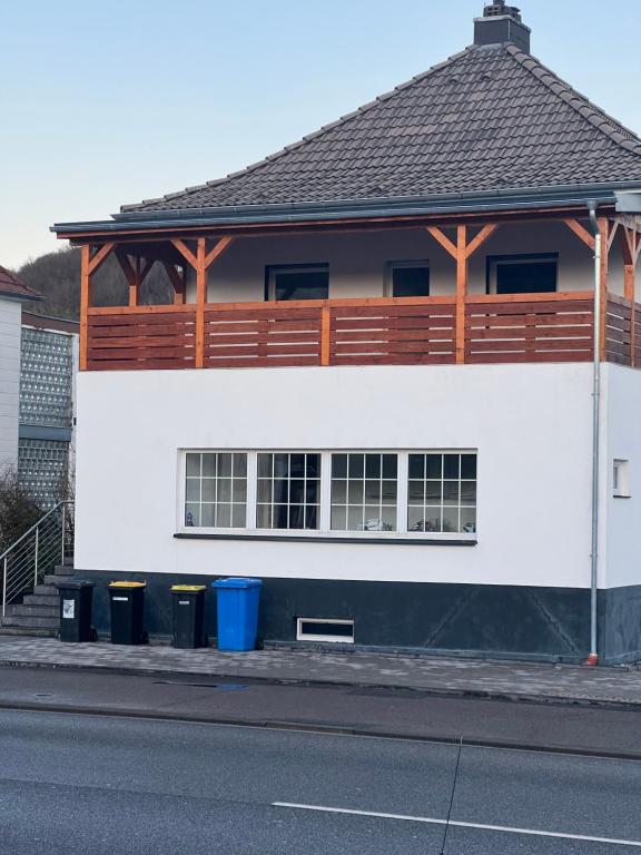 a white building with a wooden roof and trash cans at Ferienwohnung-Monteurwohnung in Homburg