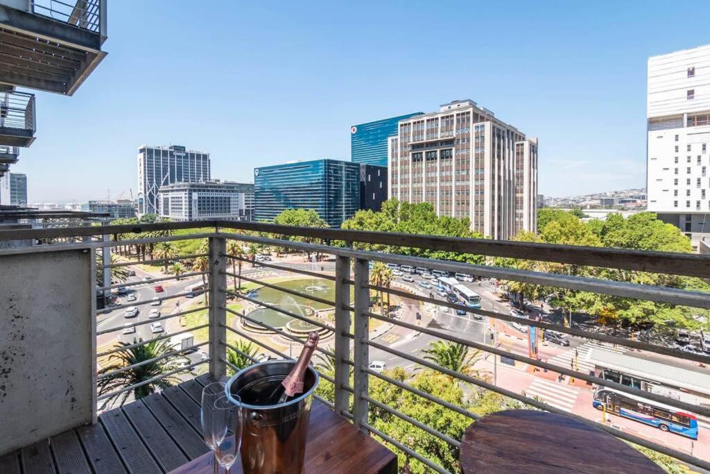 a drink on a table on a balcony with a city at Chic 1-Bedroom Apartment In The Heart Of The City in Cape Town