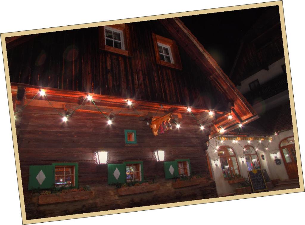 a wooden house with christmas lights on it at Gasthof & Buschenschank Windisch in Gundersdorf